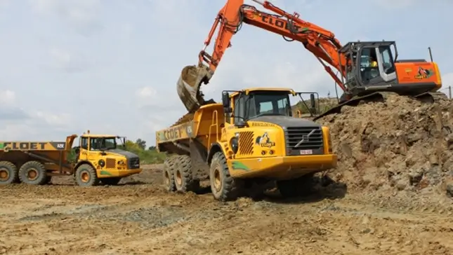 Graafmachine laadt dumpers van Cloet bij grondwerken
